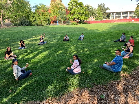plant pathology graduate student association students sitting in a wide circle eating ice cream in an outdoors open green space