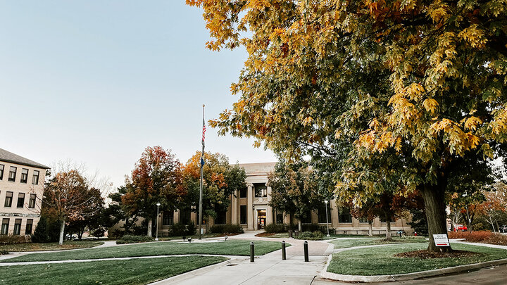 The Chase building on East Campus is framed by fall gold leaves on trees.