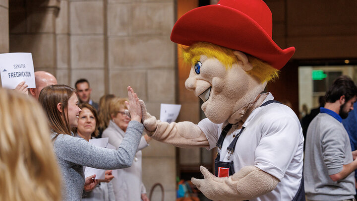 Herbie high fives Liz Husmann of UNMC during the I Love NU Day Celebration in the capitol Rotunda.