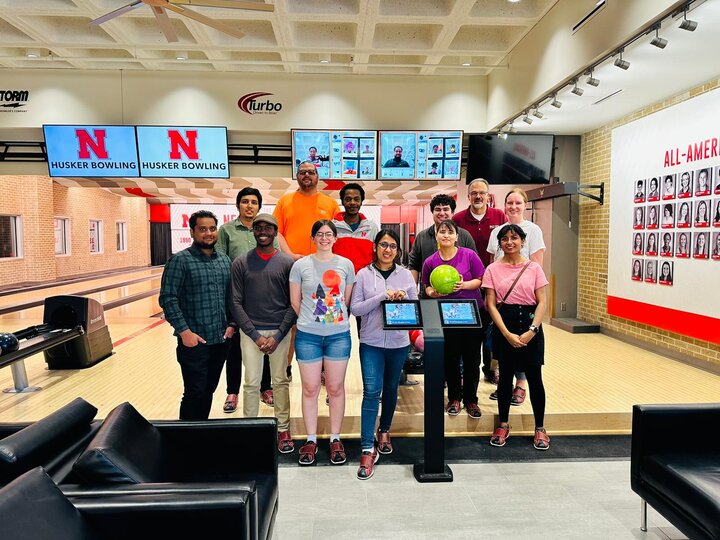 Students stand in front of bowling lanes holding bowling balls